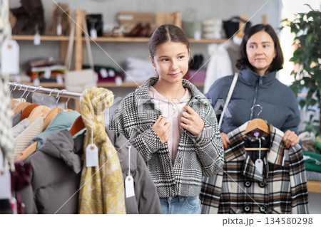 Teenage girl with her mother try on coat in store 134580298