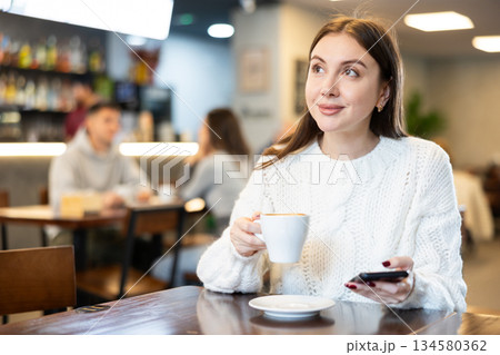 Young woman with phone in cafe Young woman with phone in cafe 134580362