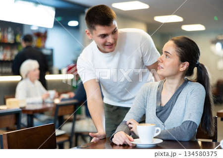 woman is sitting at a table in a coffee shop and does not want to meet a guy woman is sitting at a table in a coffee shop and does not want to meet a guy 134580375