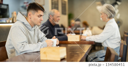 Guy whiles away time and drink coffee in cafe 134580451