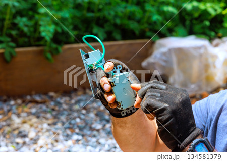 Electrician uses tools to fix circuit board while sitting in construction area Electrician uses tools to fix circuit board while sitting in construction area 134581379