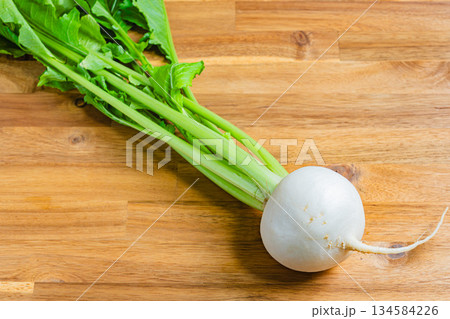 木目テーブルと竹ざるに盛られた新鮮なかぶ 134584226