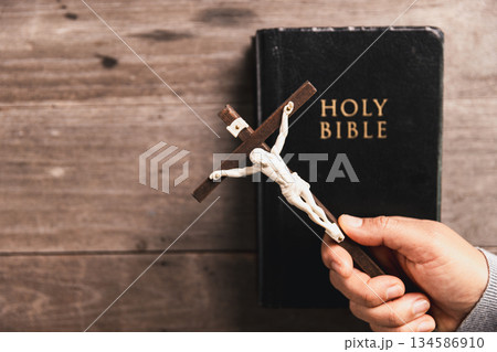 Hands in prayer above Holy Bible on wooden table, symbolizing Christian faith, worship, devotion, trust in God, spiritual religious background with copy space for church, prayer, meditation concepts. Hands in prayer above Holy Bible on wooden table, symbolizing Christian faith, worship, devotion, trust in God, spiritual religious background with copy space for church, prayer, meditation concepts. 134586910