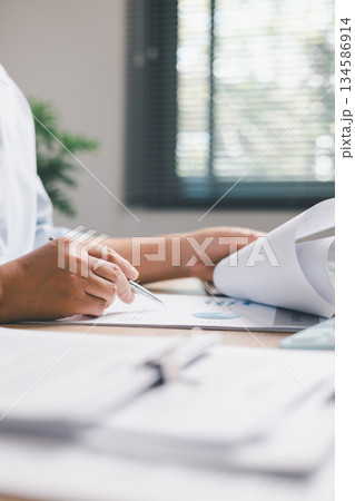 Office worker analyzing business reports and financial charts, reviewing data and writing notes to support planning, strategy and professional decision-making in a modern workplace environment. Office worker analyzing business reports and financial charts, reviewing data and writing notes to support planning, strategy and professional decision-making in a modern workplace environment. 134586914