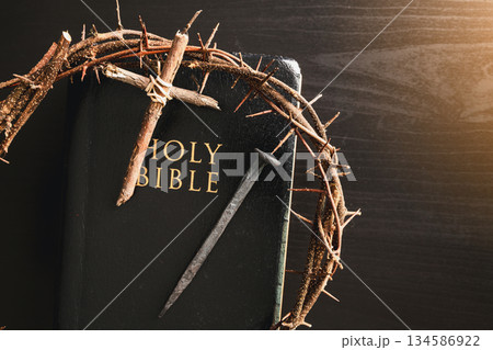 Crown of thorns, wooden cross, iron nail placed on Holy Bible, symbolizing Christian faith, sacrifice, crucifixion, Easter reflection, religion background for worship, spiritual concept 134586922