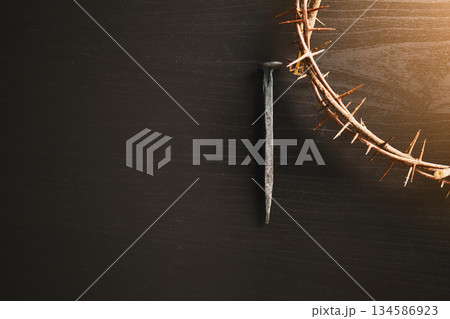 Crown of thorns, wooden cross, iron nail placed on Holy Bible, symbolizing Christian faith, sacrifice, crucifixion, Easter reflection, religion background for worship, spiritual concept 134586923