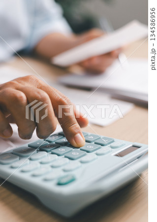 Close-up of office worker calculating financial data with calculator while reviewing receipts, documents, representing accounting tasks, budgeting, expense management, professional financial workflow. 134586956