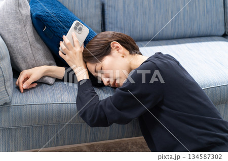 スマホを持って寝落ちする女性 134587302
