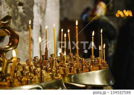 Candles in a Christian Orthodox church background. Flame of candles in the dark sacred interior of the temple 134587599