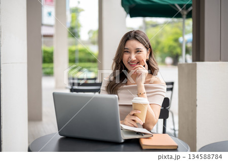 Long hair asian woman smiling with hand touching cheek while holding coffee cup on cafe black table. Long hair asian woman smiling with hand touching cheek while holding coffee cup on cafe black table. 134588784