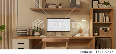 Blank screen computer on wooden table and a chair under hanging display shelf in a cosy study room. 134589237