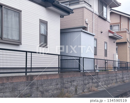 住宅街にある擁壁の上にフェンスと隣り合う戸建て住宅 住宅街にある擁壁の上にフェンスと隣り合う戸建て住宅 134590519