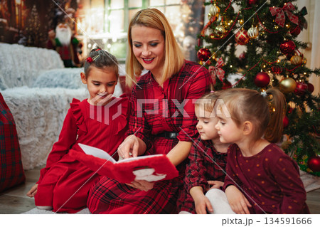 Mother reading Christmas storybook to children during holiday season Mother reading Christmas storybook to children during holiday season 134591666