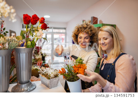 Friends enjoying a lively afternoon picking flowers in a cheerful little shop together Friends enjoying a lively afternoon picking flowers in a cheerful little shop together 134591753