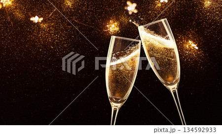 Two elegant champagne flutes clinking against a sparkling golden background 134592933