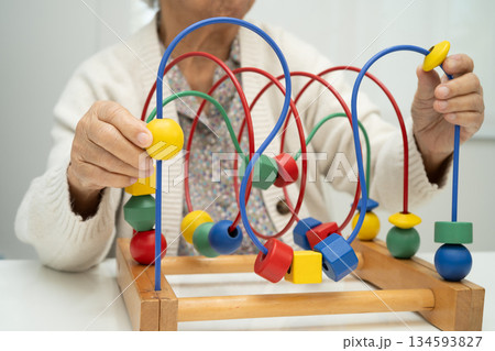Asian elderly woman playing enhancing skill board game. 134593827
