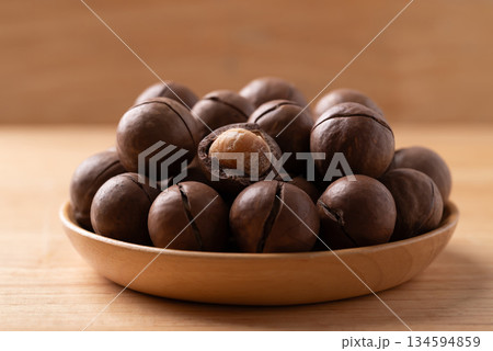 Macadamia nuts in a bowl on wooden background 134594859