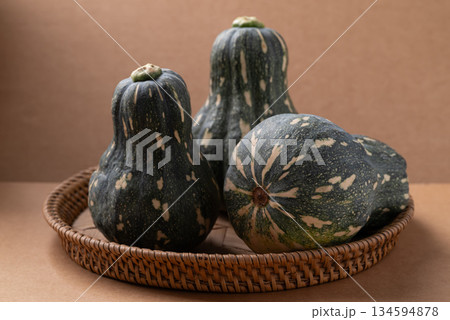 Green butternut squash pumpkin in basket on brown background Green butternut squash pumpkin in basket on brown background 134594878