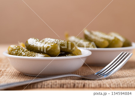 Pickled cucumber or Gherkin pickle in a bowl with fork on brown background Pickled cucumber or Gherkin pickle in a bowl with fork on brown background 134594884