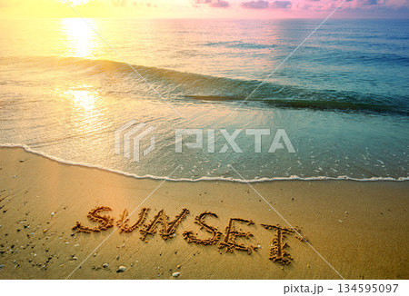 Seascape in the evening with a wave and word Sunset. Sandy beach during sunset 134595097