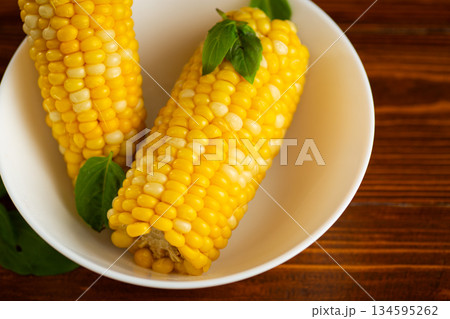 two ears of boiled corn in a white plate 134595262