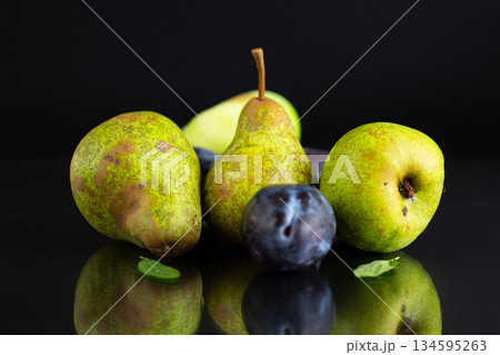 Ripe pears and plums on a black background 134595263