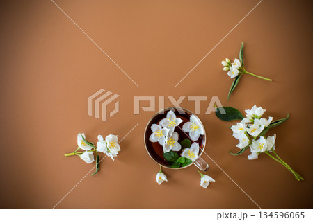 Jasmine and green tea in a transparent teapot close-up on a brown background Jasmine and green tea in a transparent teapot close-up on a brown background 134596065