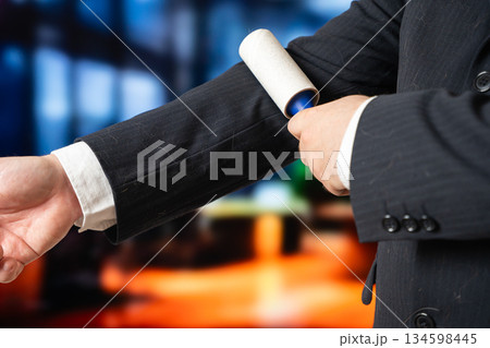 A businessman cleans his suit with a roller. Keeping clothes clean when you have pets. Pet hair problem. 134598445