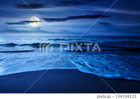 sand beach at the sea for summer vacation concept. beautiful night at perfect coast with calm waves and clouds on sky in full moon light. landscape for finance investment or abstract concepts 134599123