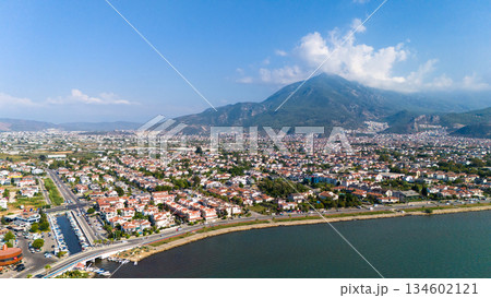 Aerial view of Fethiye coastal city in Turkey with residential area, waterfront road, sea and mountains in the background. Sunny day urban landscape by the Mediterranean coast. Aerial view of Fethiye coastal city in Turkey with residential area, waterfront road, sea and mountains in the background. Sunny day urban landscape by the Mediterranean coast. 134602121