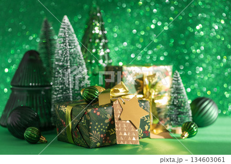 Christmas Gifts with Mini Trees and Green-Gold Ornaments on Festive Background Christmas Gifts with Mini Trees and Green-Gold Ornaments on Festive Background 134603061