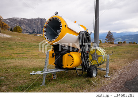 Snowmaking machine on alpine ski slope in Dolomites mountains 134603283