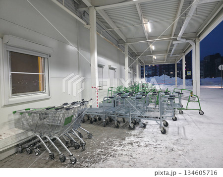 Snowy Supermarket Cart Bay at Night with Stacked Carts 134605716