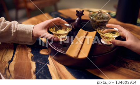 Two people holding tea cups during relaxed home tea ritual Two people holding tea cups during relaxed home tea ritual 134605914