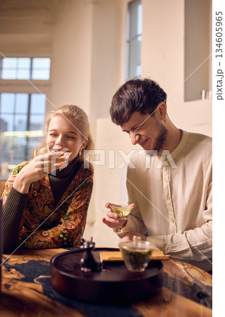 Young couple toasting tea cups during calm tea ceremony at table. Young couple toasting tea cups during calm tea ceremony at table. 134605965