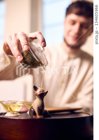 Close up of tea pouring over ceramic figurine during ceremony Close up of tea pouring over ceramic figurine during ceremony 134605966