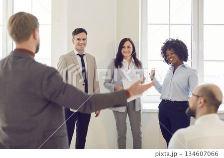 Company employees standing in a circle and discussing work project in office on a meeting. Company employees standing in a circle and discussing work project in office on a meeting. 134607066
