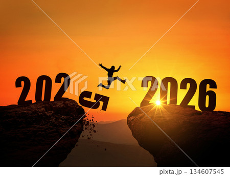Man jumping on cliff 2026 over the precipice with stones at amazing sunset. New Year's concept. 2025 falls into the abyss. Welcome 2026. People enters the year 2026, creative idea. 134607545