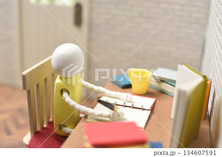ノートに書き留めている木製人形の写真　勉強　執筆活動　宿題 134607591