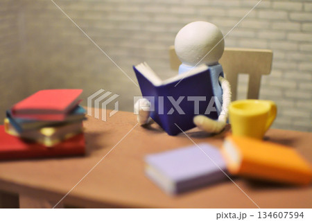 読書をする木製人形の写真　積まれた本　趣味の時間　勉強　ミニチュア 134607594