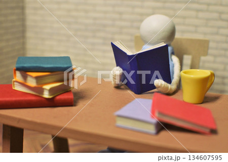 読書をする木製人形の写真　積まれた本　趣味の時間　勉強　ミニチュア 134607595