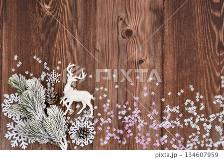 Snow-covered fir branch and deer on the background of a dark wooden table with snowflakes. 134607959