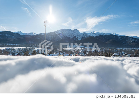 bright winter landscape featuring snow-covered ground, a small town, and distant mountain peaks under a clear blue sky. Sunlight creates a vivid, crisp atmosphere ideal. Holidays. Zakopane, Poland 134608383