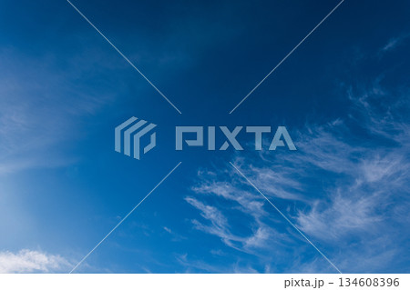Deep blue sky background with dynamic white cirrus clouds. Ideal copy space for weather, nature, or abstract design concepts. Peaceful and abstract nature background. Deep blue sky background with dynamic white cirrus clouds. Ideal copy space for weather, nature, or abstract design concepts. Peaceful and abstract nature background. 134608396