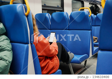 Passenger sitting and scrolling on smartphone with blank screen inside public transport vehicle Passenger sitting and scrolling on smartphone with blank screen inside public transport vehicle 134610400