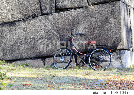 Bicycles, a popular transportation in Japan, parked on the sidewalk near a massive rock wall. Bicycles, a popular transportation in Japan, parked on the sidewalk near a massive rock wall. 134610459