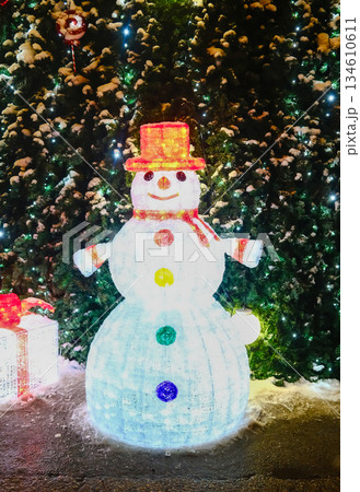 Illuminated snowman figure near Christmas tree Illuminated snowman figure near Christmas tree 134610611