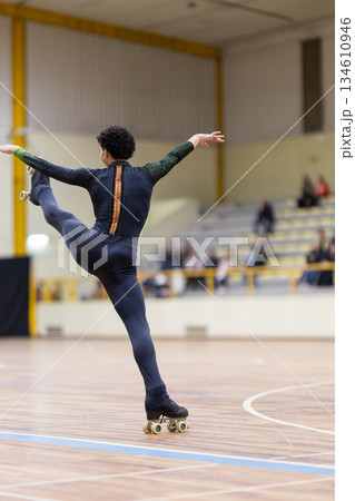 Athlete performing artistic roller skate figure on wooden floor Athlete performing artistic roller skate figure on wooden floor 134610946