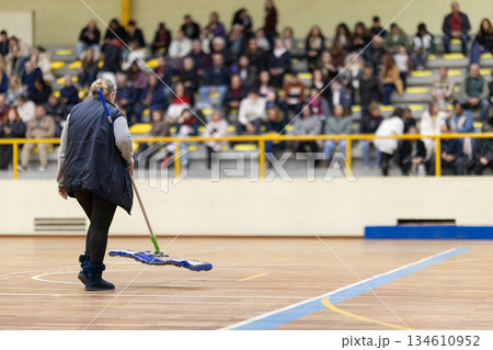 Person cleaning gymnasium court floor during event 134610952