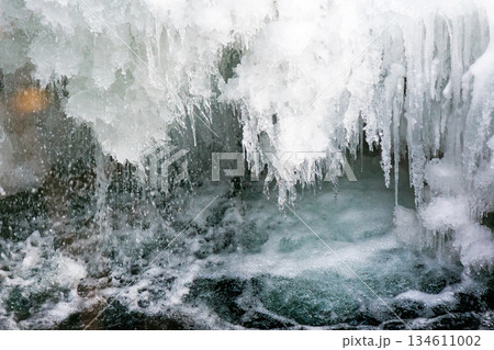 frozen waterfall close up view. icicles hanging above water. cold winter landscape photography on river tyrychka of transcarpathia ukraine. seasonal nature texture. background for climate change frozen waterfall close up view. icicles hanging above water. cold winter landscape photography on river tyrychka of transcarpathia ukraine. seasonal nature texture. background for climate change 134611002